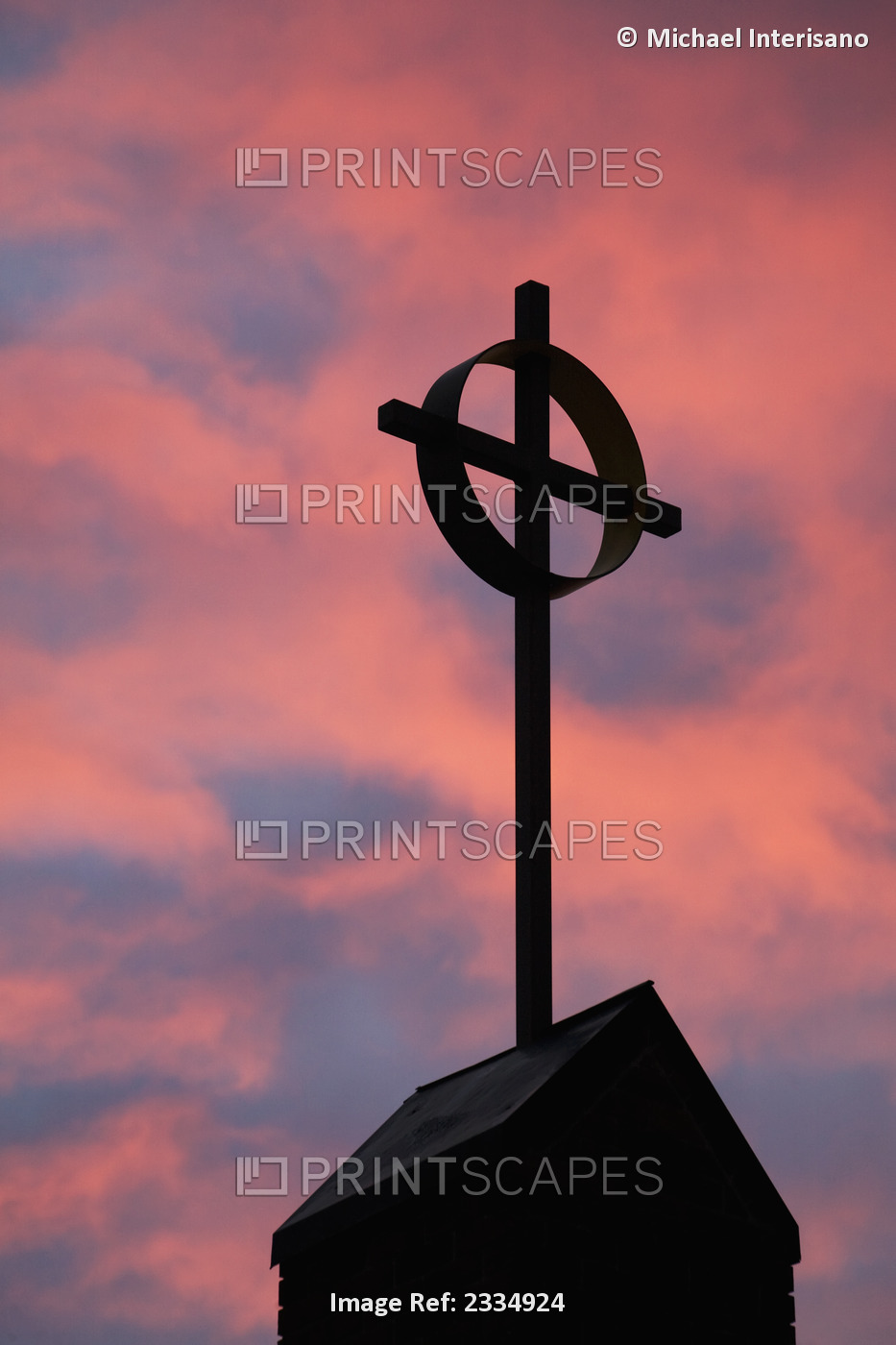 Silhouette of a cross on church steeple with fiery cloud cover in the sky at ...