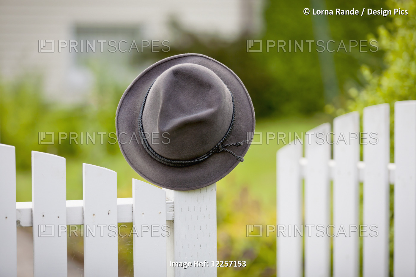 A Hat Hanging On The Post Of A White Picket Fence; Vancouver, British Columbia, ...