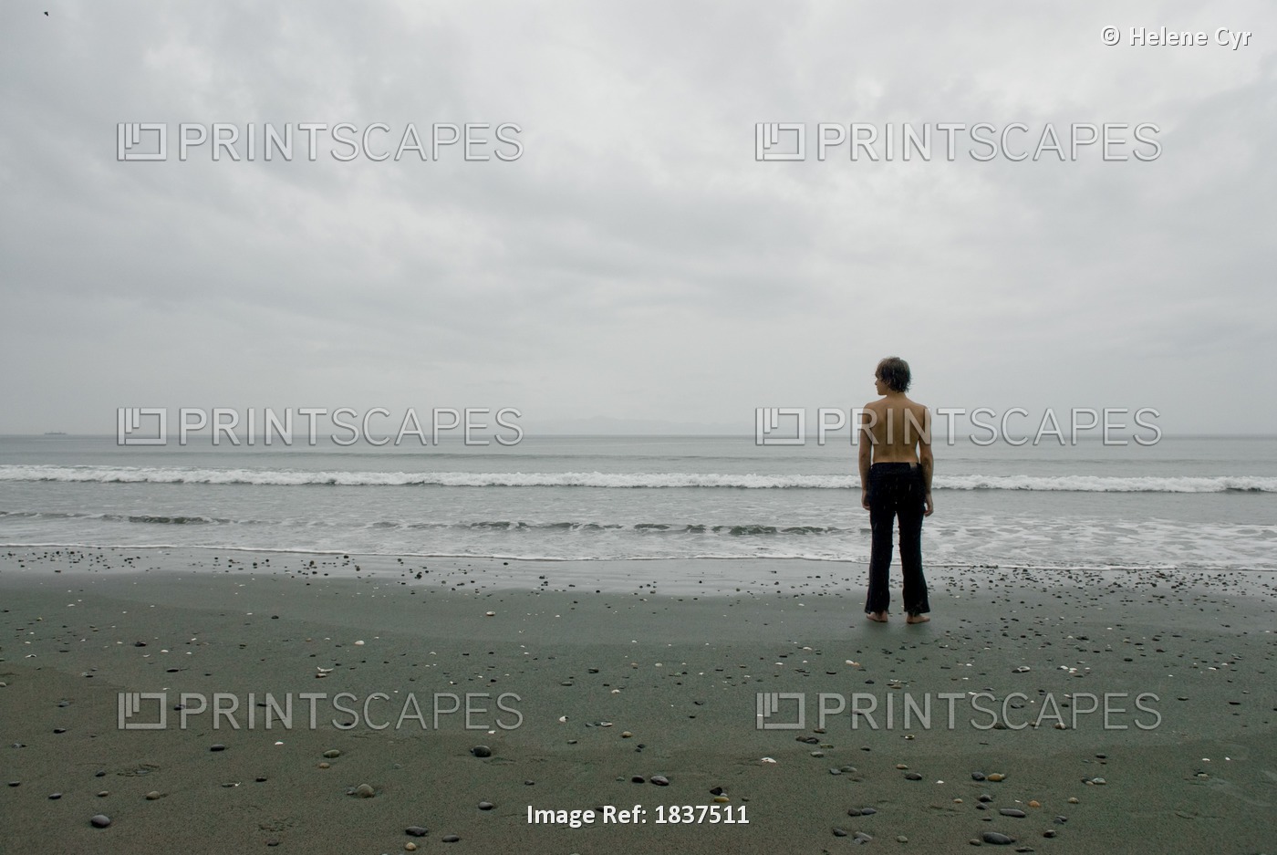 Woman Standing Alone On Beach Under Cloudy Skies