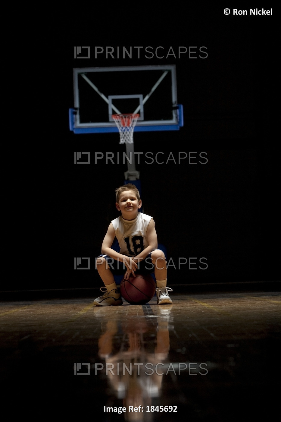 Young Boy Sitting On Basketball Court