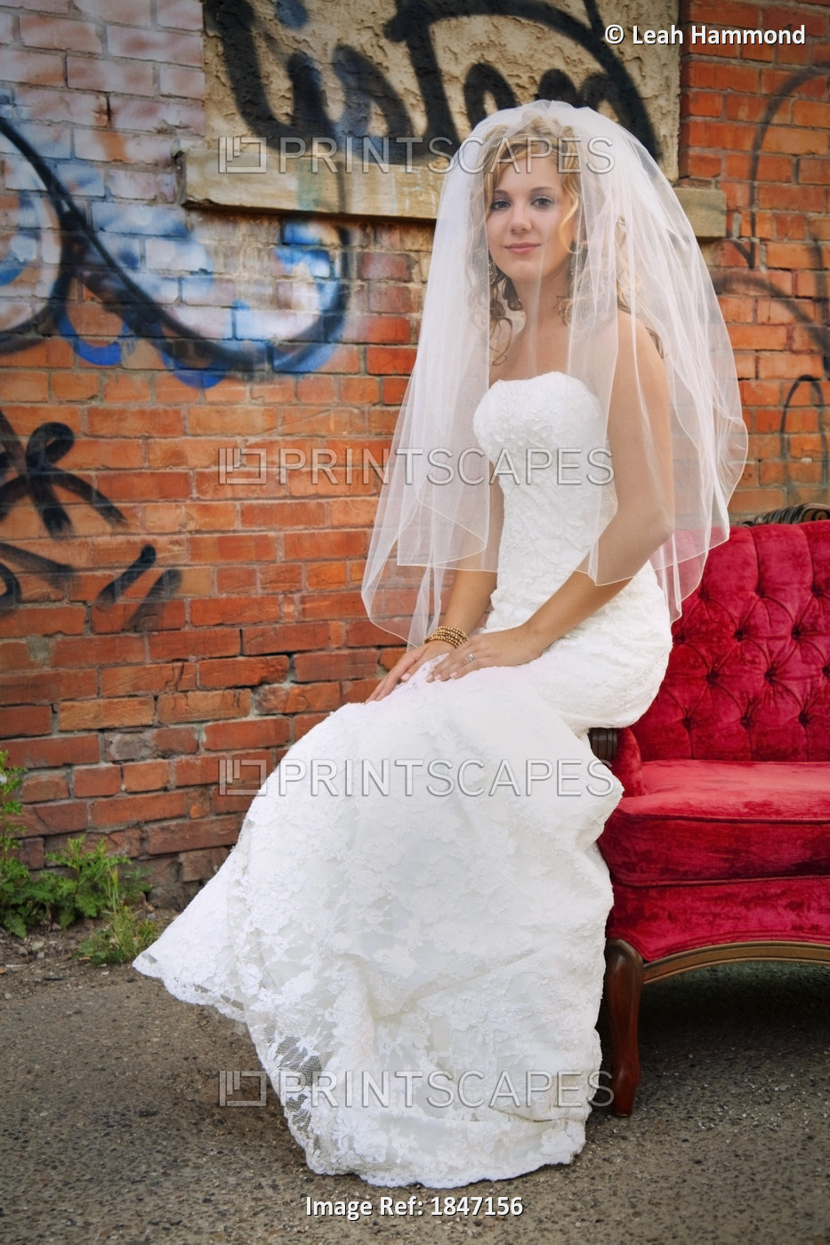 Bride Sitting On The Edge Of A Red Sofa Outdoors