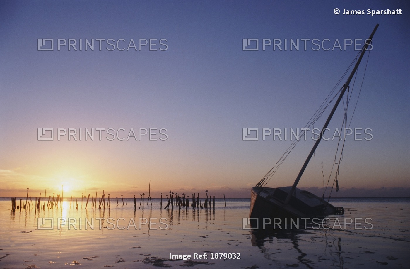 Partly Submerged And Keeling Sail Boat In Silhouette At Sunset