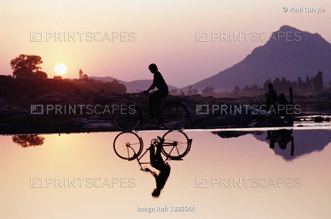 Bicyclist Crossing Shallow River At Sunset With Women In Background Doing ...