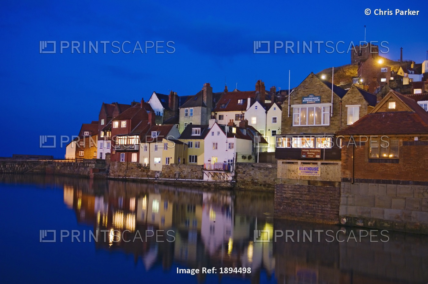 UK, Yorkshire, Houses reflecting in water at dusk; Whitby