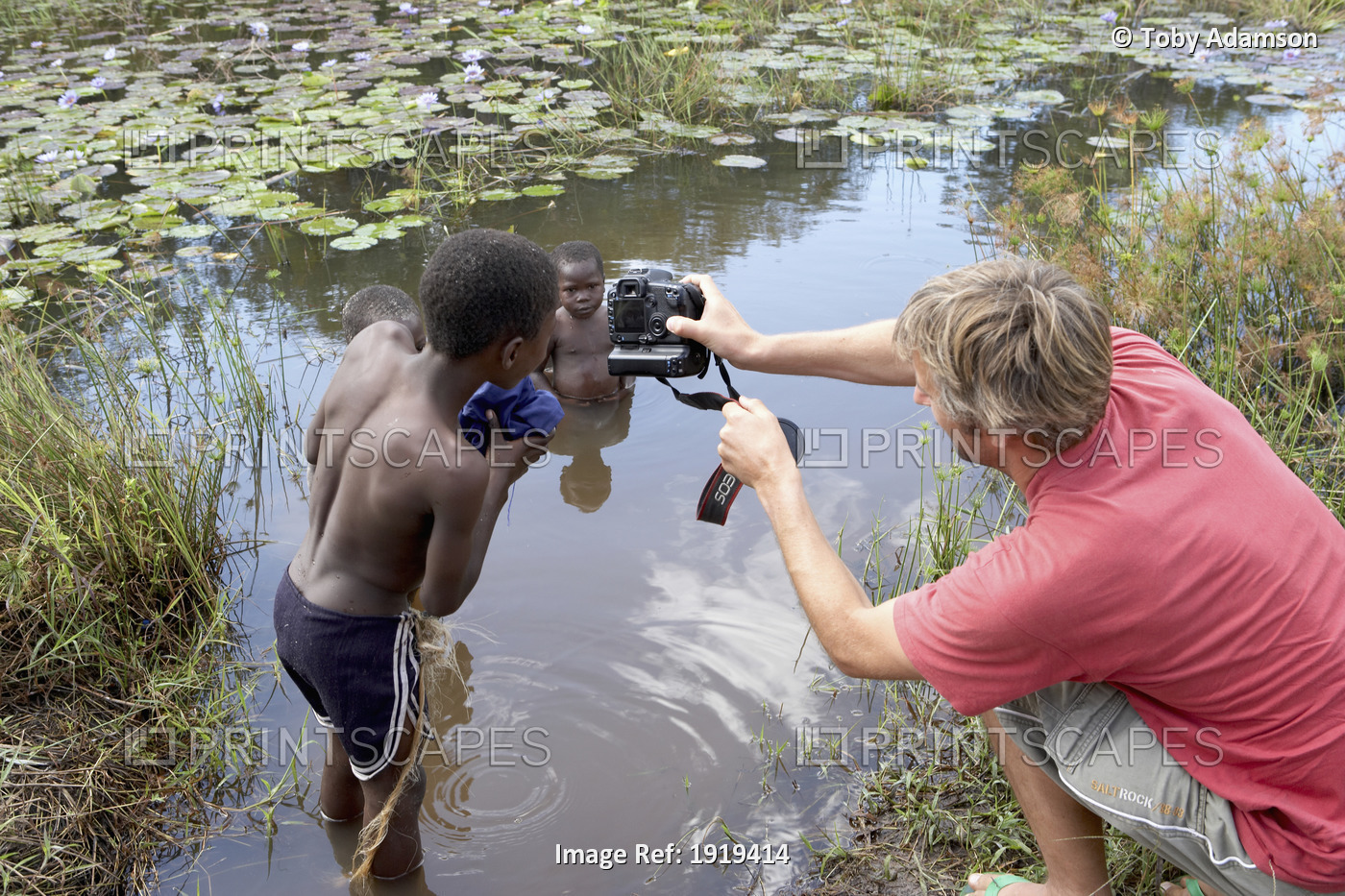Photographer Taking Photos Of Children In River, Tanzania