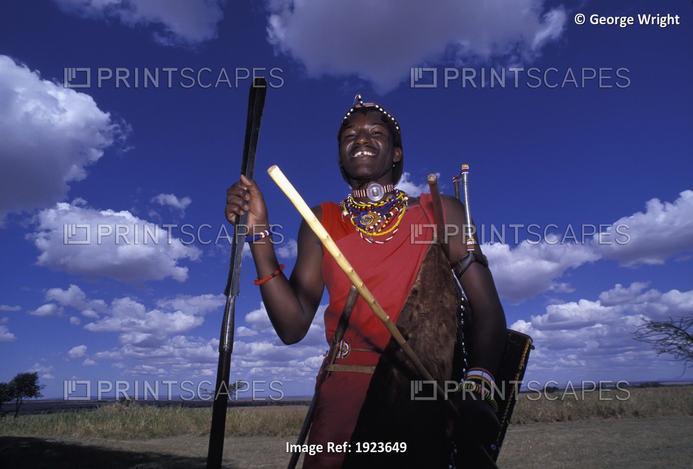 Tribal man stands posing with a smile, wearing traditional clothing and holding ...