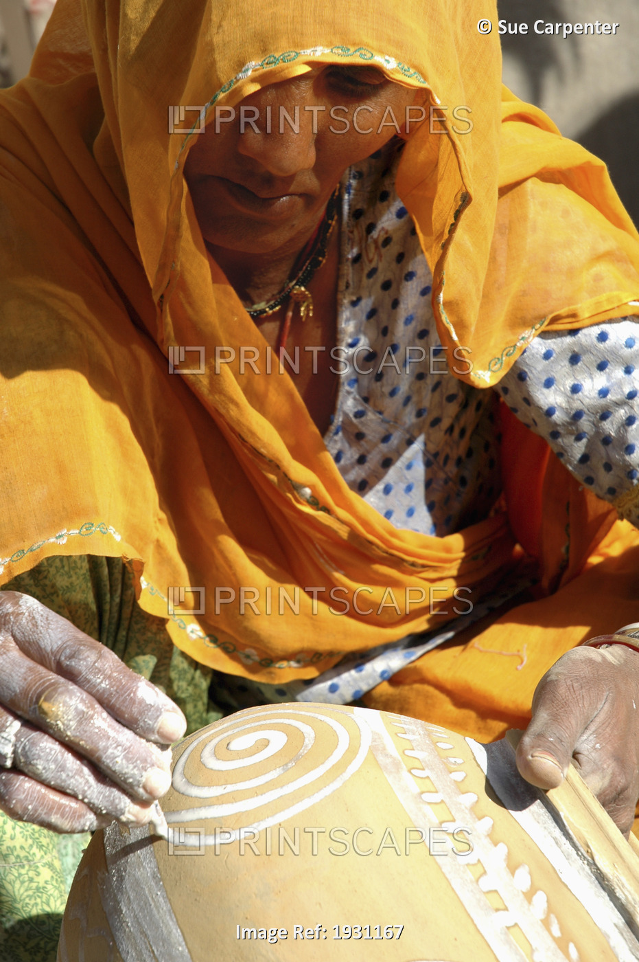 Close-up on a woman in orange sari painting a terracotta pot, Nimaj, Rajasthan, ...