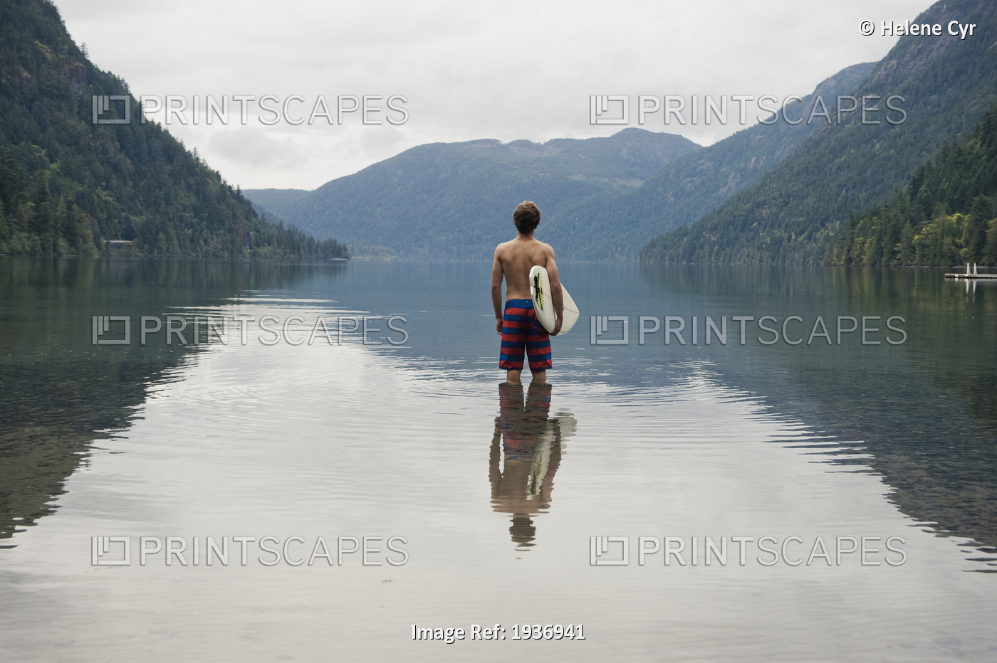 A Young Man Wearing A Swimsuit Stands In Cameron Lake; British Columbia Canada