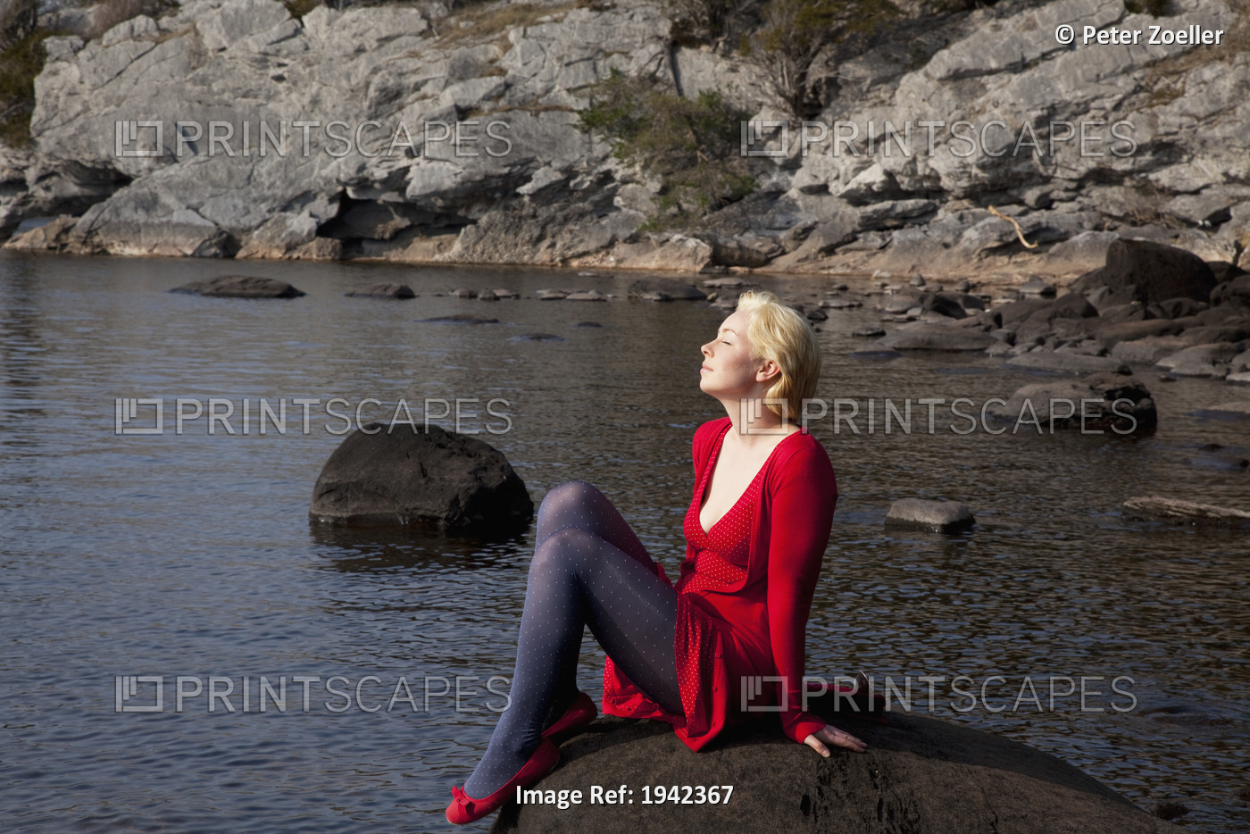 A Young Woman Basks In The Sunshine While Sitting On A Large Rock On Muckross ...