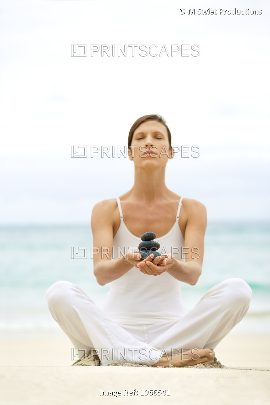 Hawaii, Woman Holding Stack Of Stones In Hands, Ocean In Background.