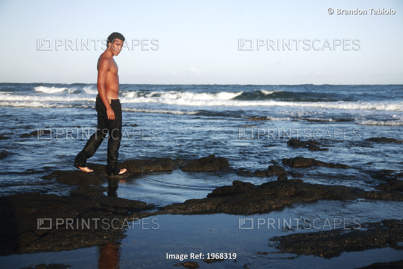 Hawaii, Oahu, Attractive Male Walking Along The Black Shoreline Rocks.