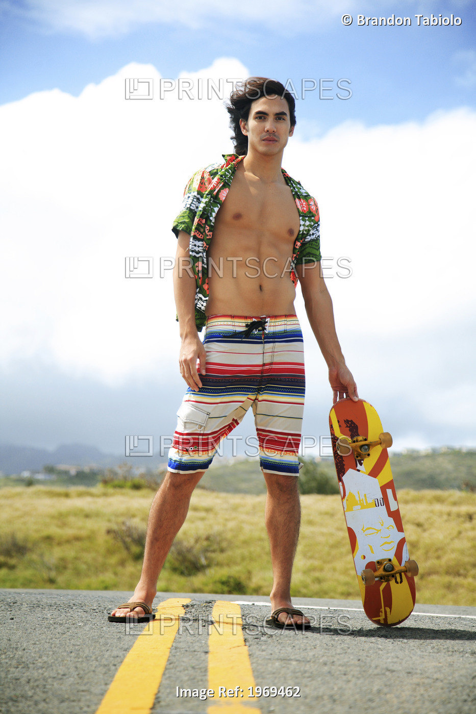 Hawaii, Oahu, Young Male Posing In Middle Of Roadway Holding A Skateboard.