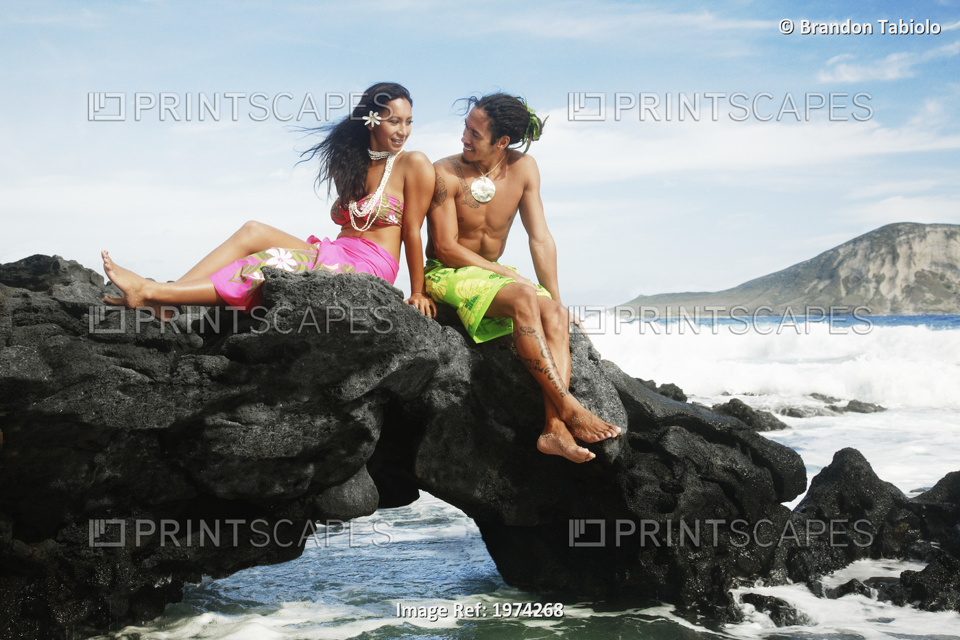 Hawaii, Oahu, Makapuu, Male And Female Hula Dancers Sit On A Rock Posing.