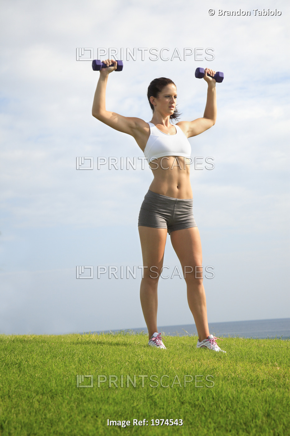 Hawaii, Oahu, Woman Excercising By Lifting Light Weights At Beach Park.
