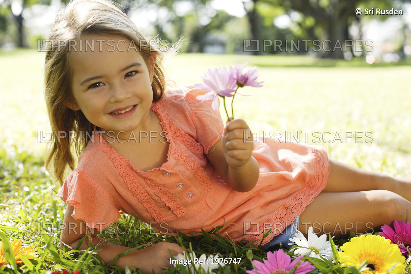 Young Girl Playing With Flowers In The Grass.