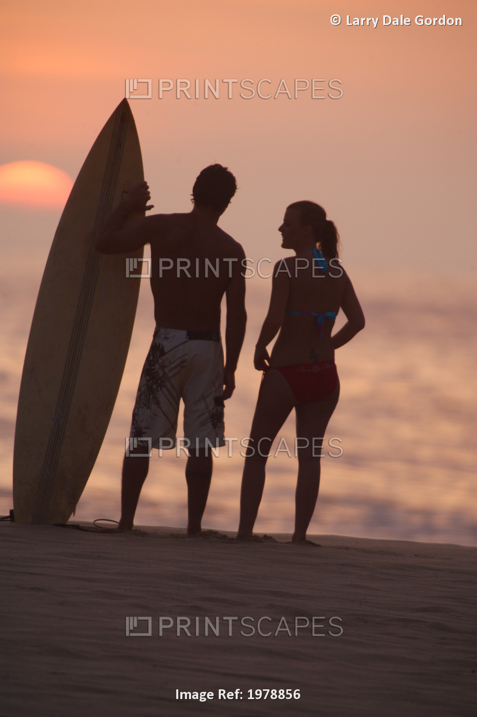USA, Hawaii, Silhouette of man and woman on beach with surfboard at sunset; Oahu