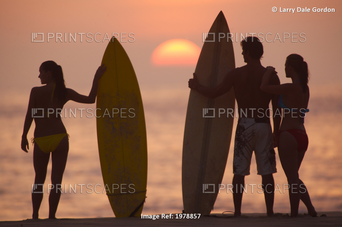 USA, Hawaii, Silhouette of man and two women on beach with surfboards at ...