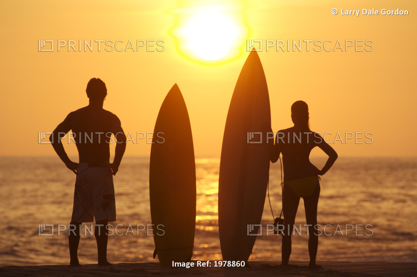 Hawaii, Oahu, Silhouette Of Man And Woman On Beach With Surfboards At Sunset.