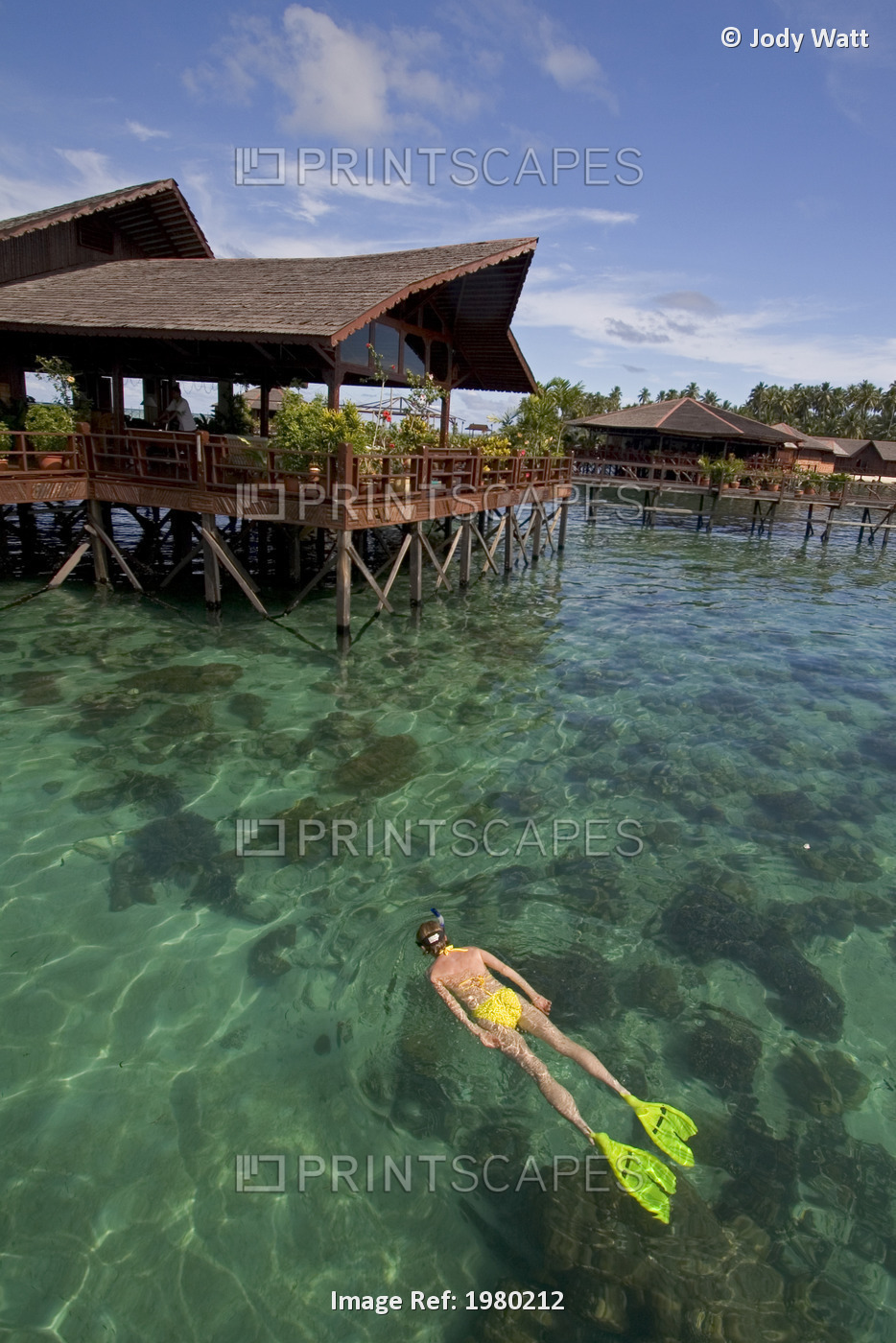 Malaysia, Woman snorkeling over coral reef below Sipidan Water Village Resort; ...