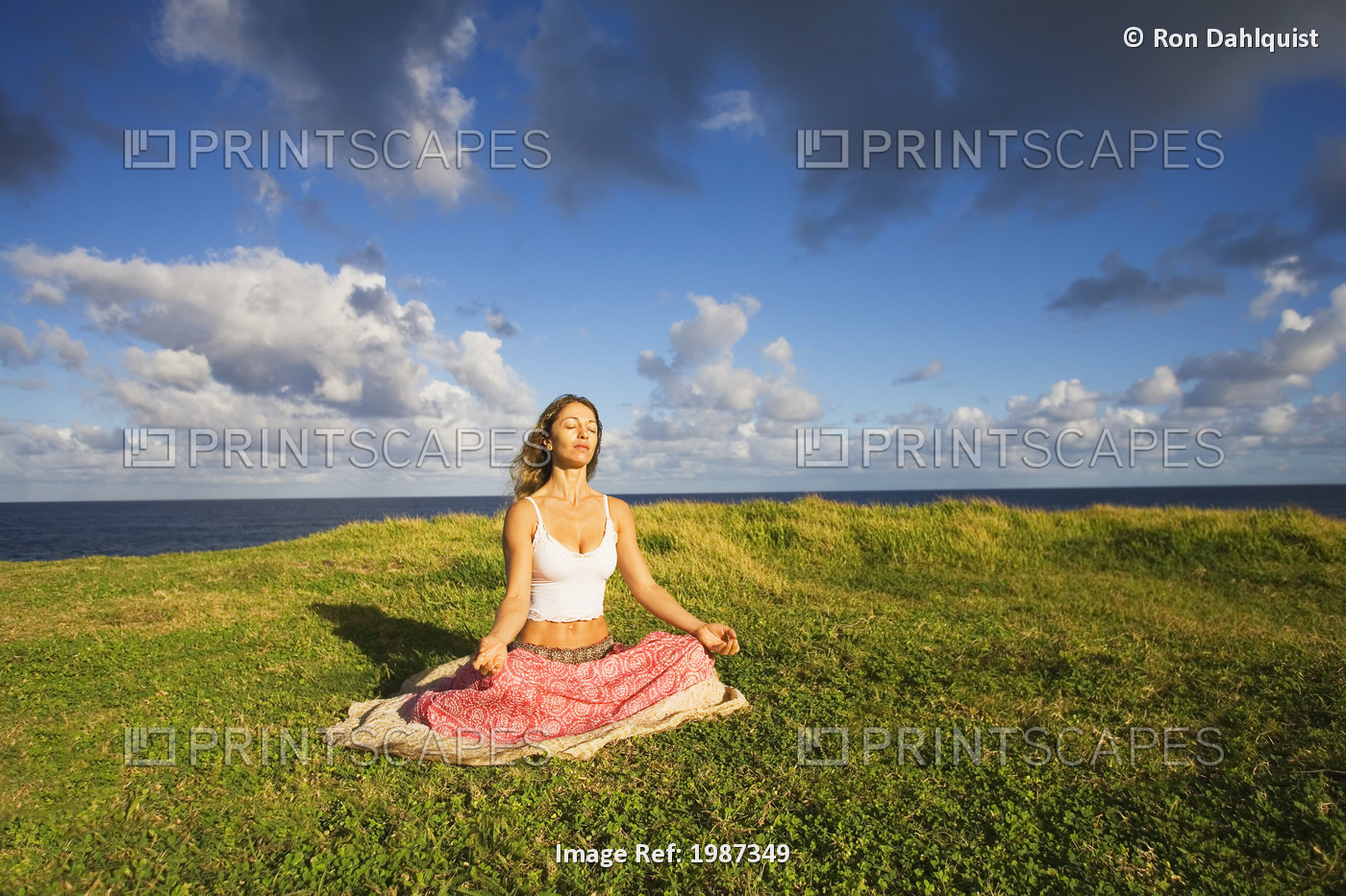 USA, Hawaii, Young woman doing yoga on grassy hill near Pacific Ocean; Maui