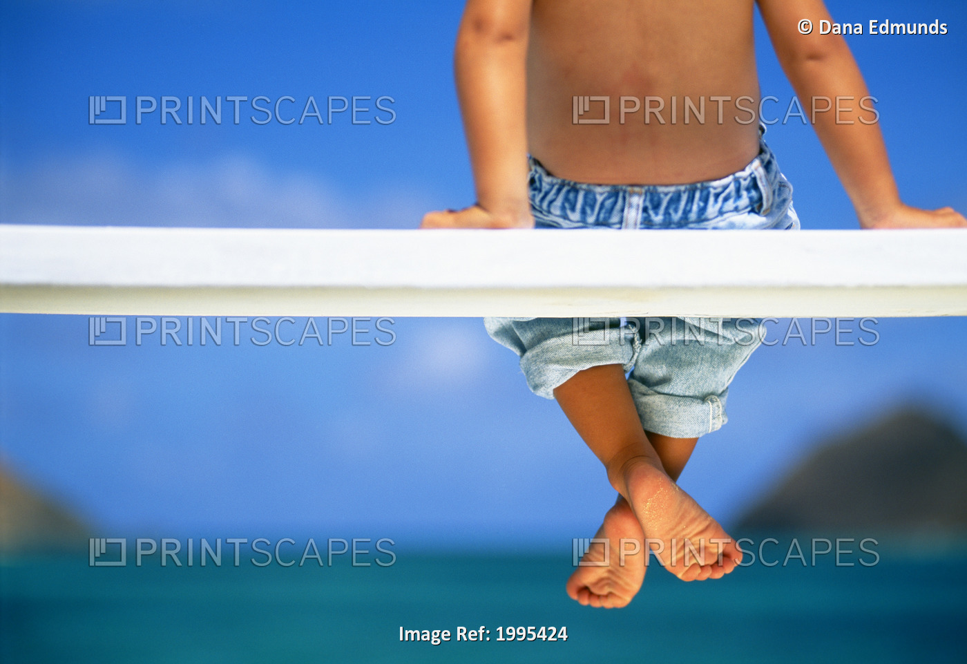 Hawaii, Legs And Feet Of Young Boy Sitting On A Bench By The Ocean