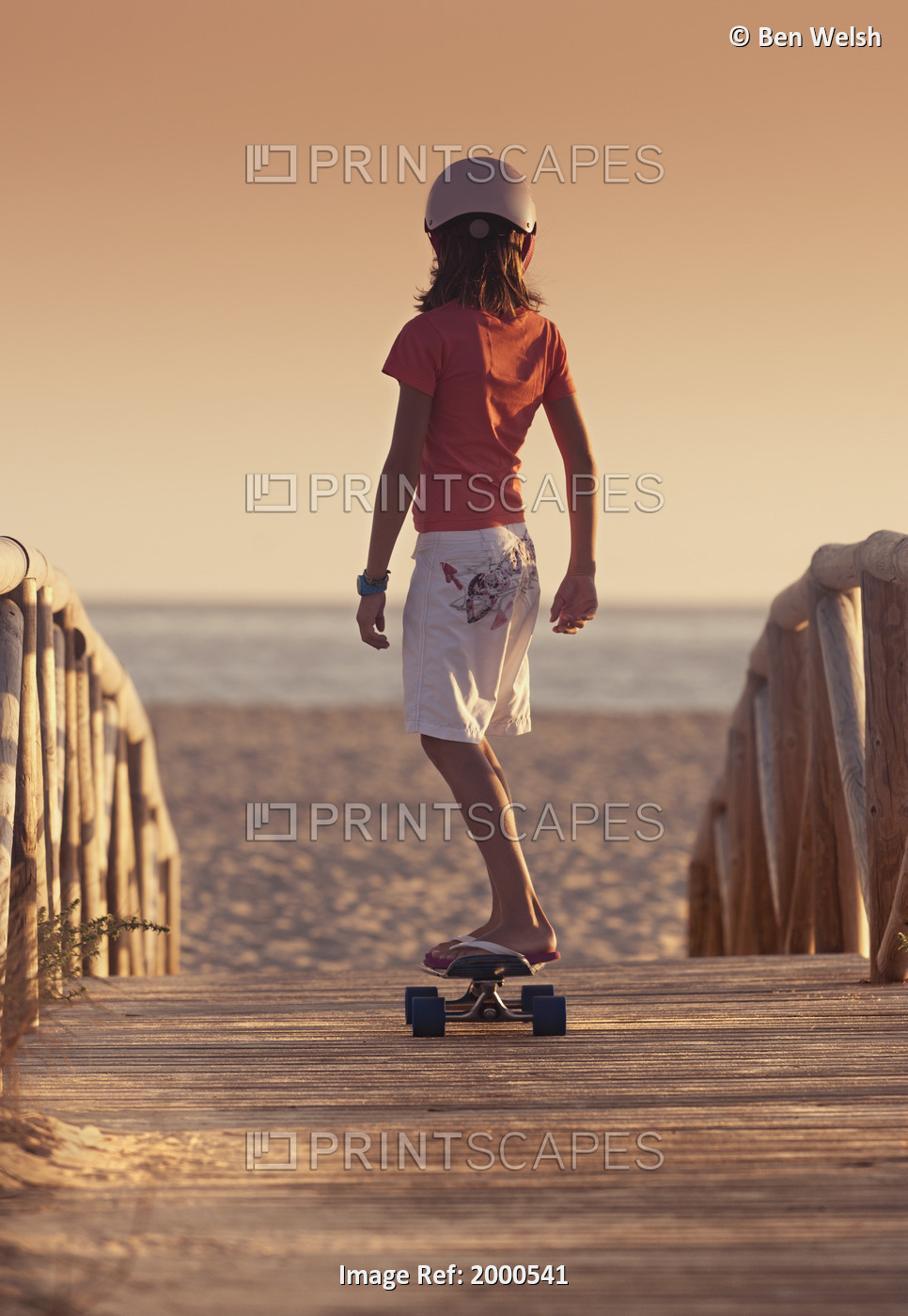 A Young Person Skateboarding With Bare Feet Over A Wooden Boardwalk Towards The ...