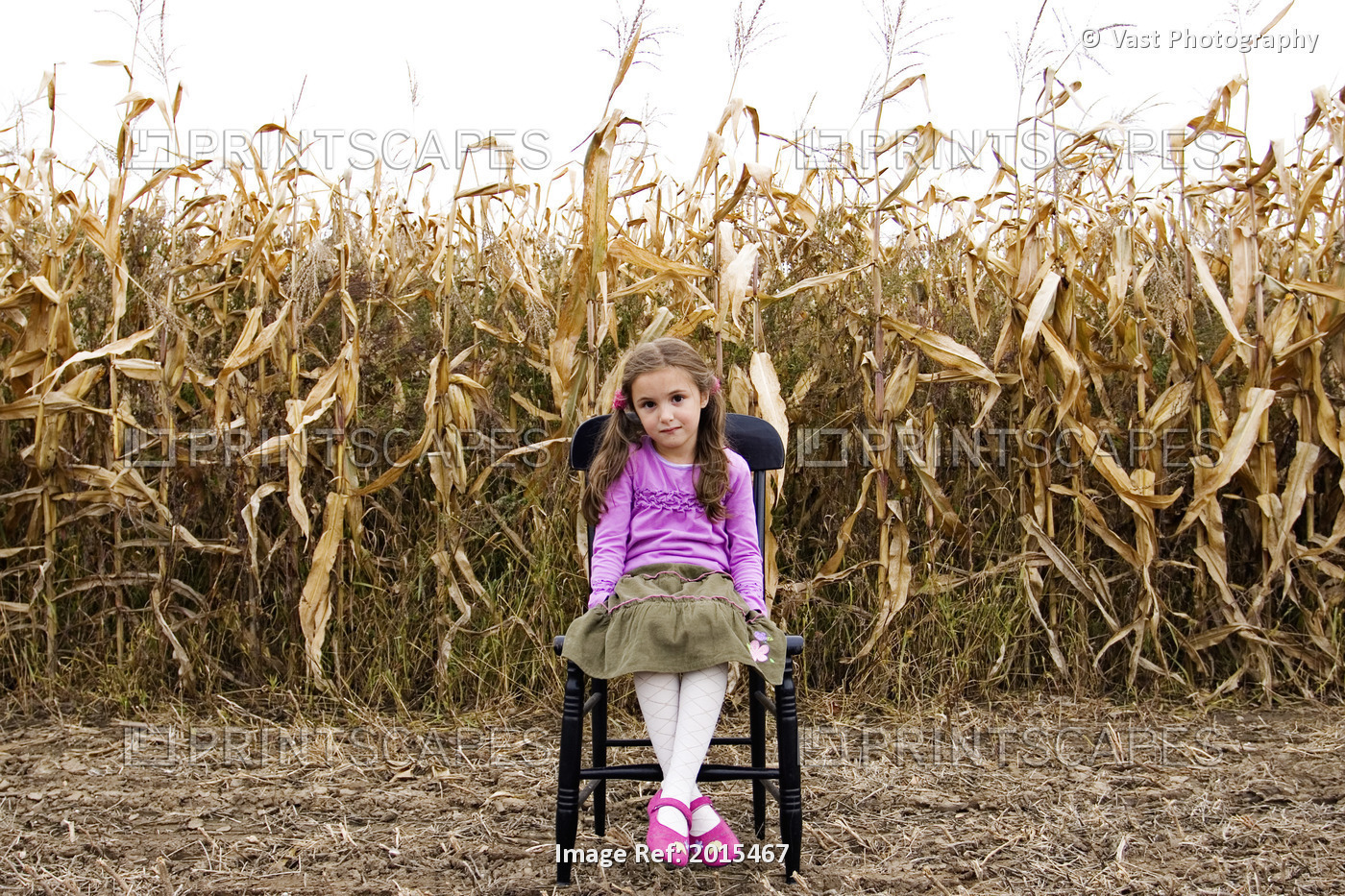 Young Girl Sitting On Chair In Corn Field