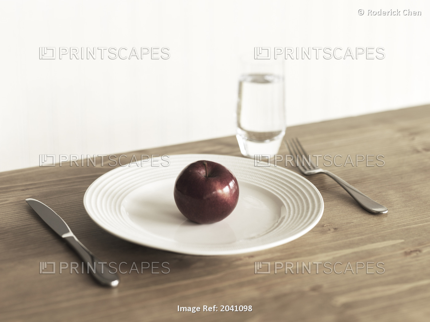 Place Setting With A Plate, A Single Apple, Knife, Fork And A Glass Of Water