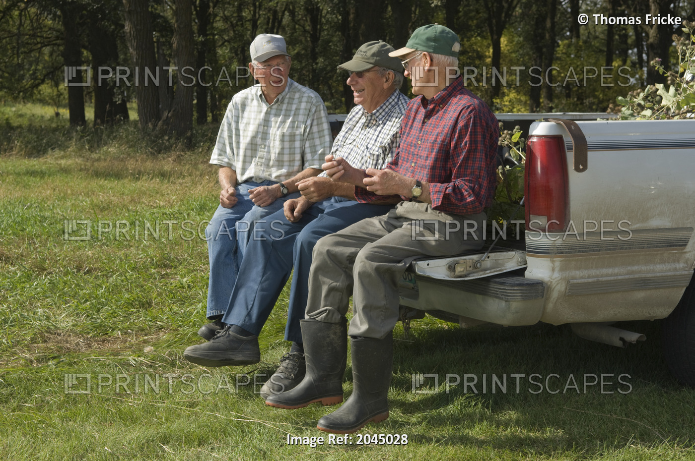 Three Senior Men Sitting On The Tail Gate Of A Pick Up Truck In Manitoba, Canada