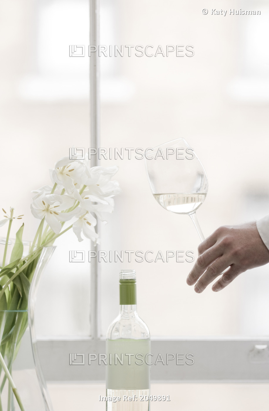 Hand Holding Glass Of White Wine With White Tulips At A Window Ledge