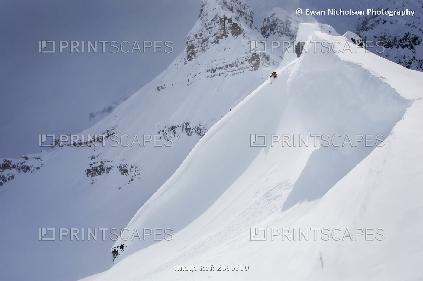 Skier On Crest Of Big Drop, Dwarfed By Mountain; Canada, British Columbia, ...