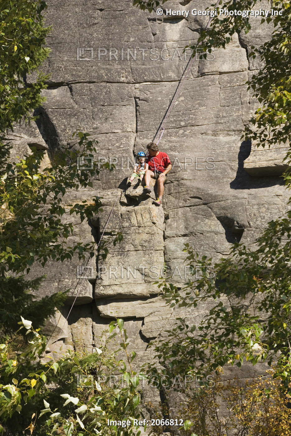 Mid-Age Man Climbing With Daughter (Age 5) Up Granite Cliff At Stone Hills Near ...