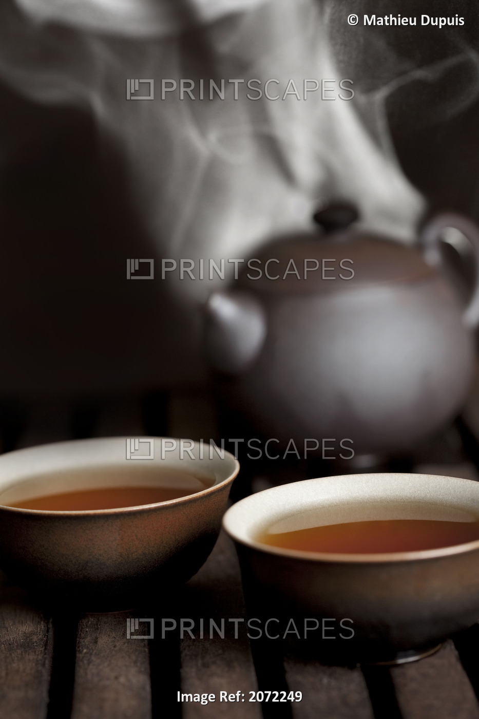 Tea In Cups With A Steaming Pot In The Background