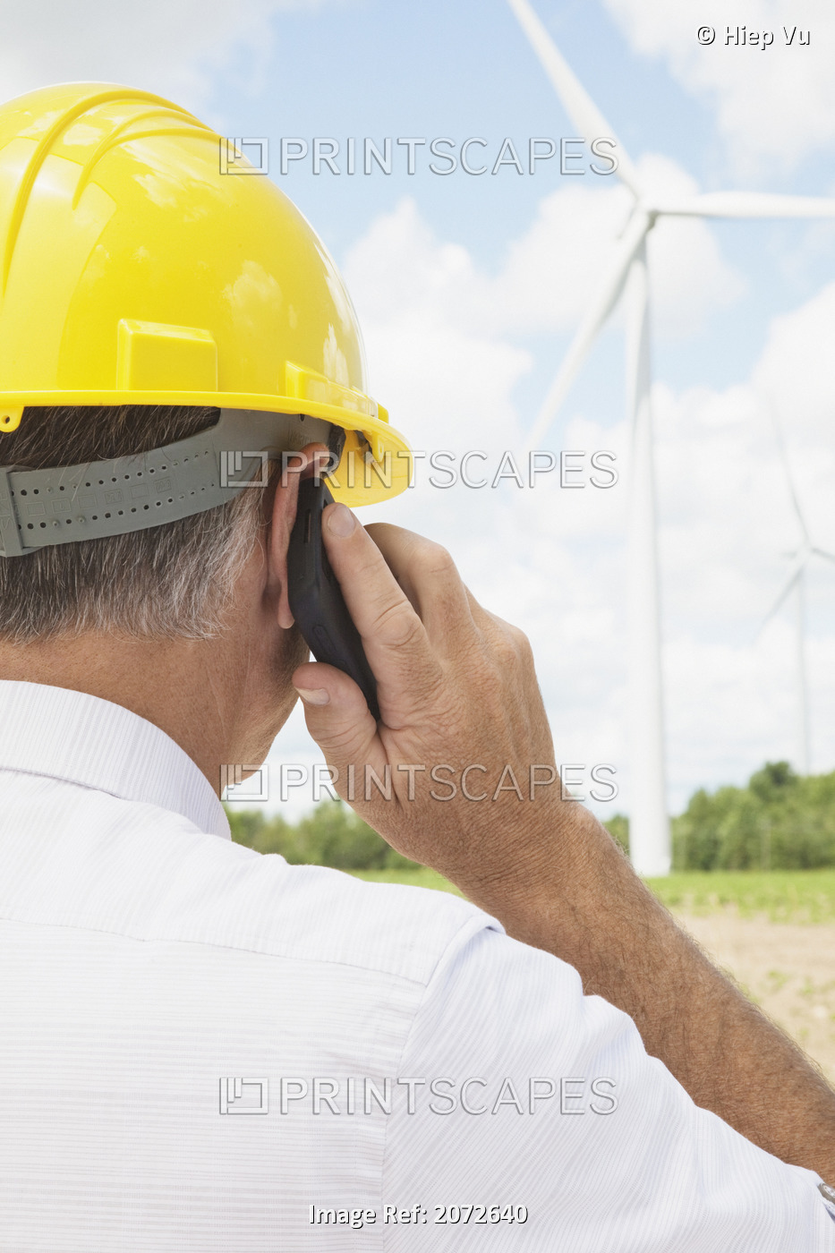 Man In Hard Hat Using Cellphone On Wind Farm, Near Shelburne, Ontario