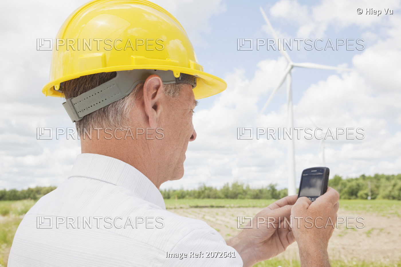 Man In Hard Hat Texting On Wind Farm, Near Shelburne, Ontario