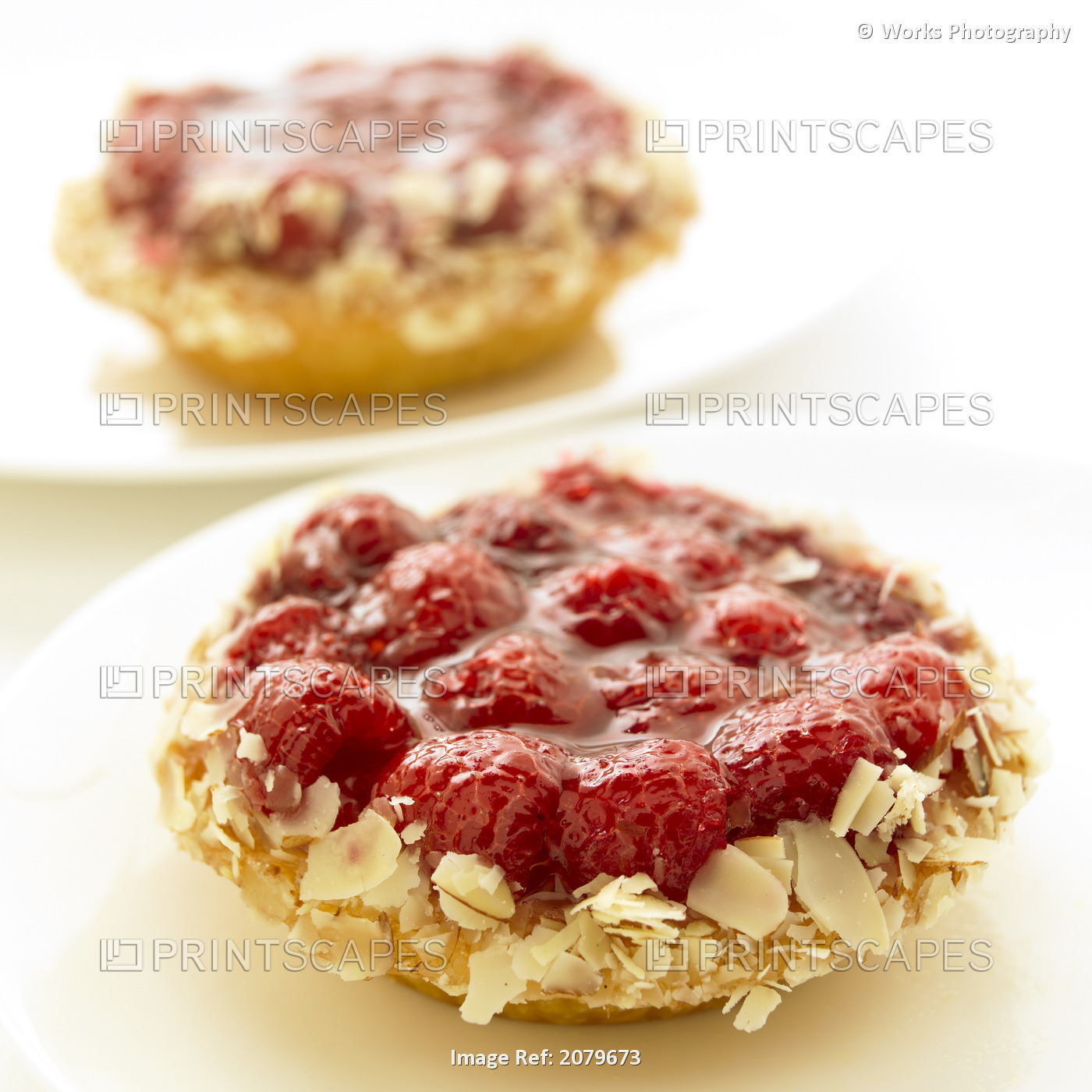 Close-Up Of Two Raspberry Tarts On White Plates.