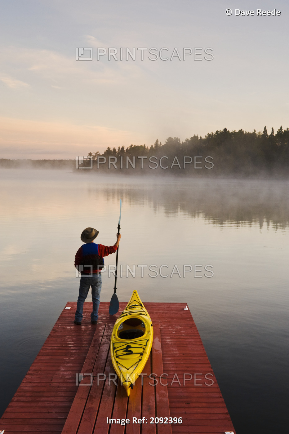 Man Standing By Kayak On Dock In Northwestern Ontario; Lake Of The Woods ...
