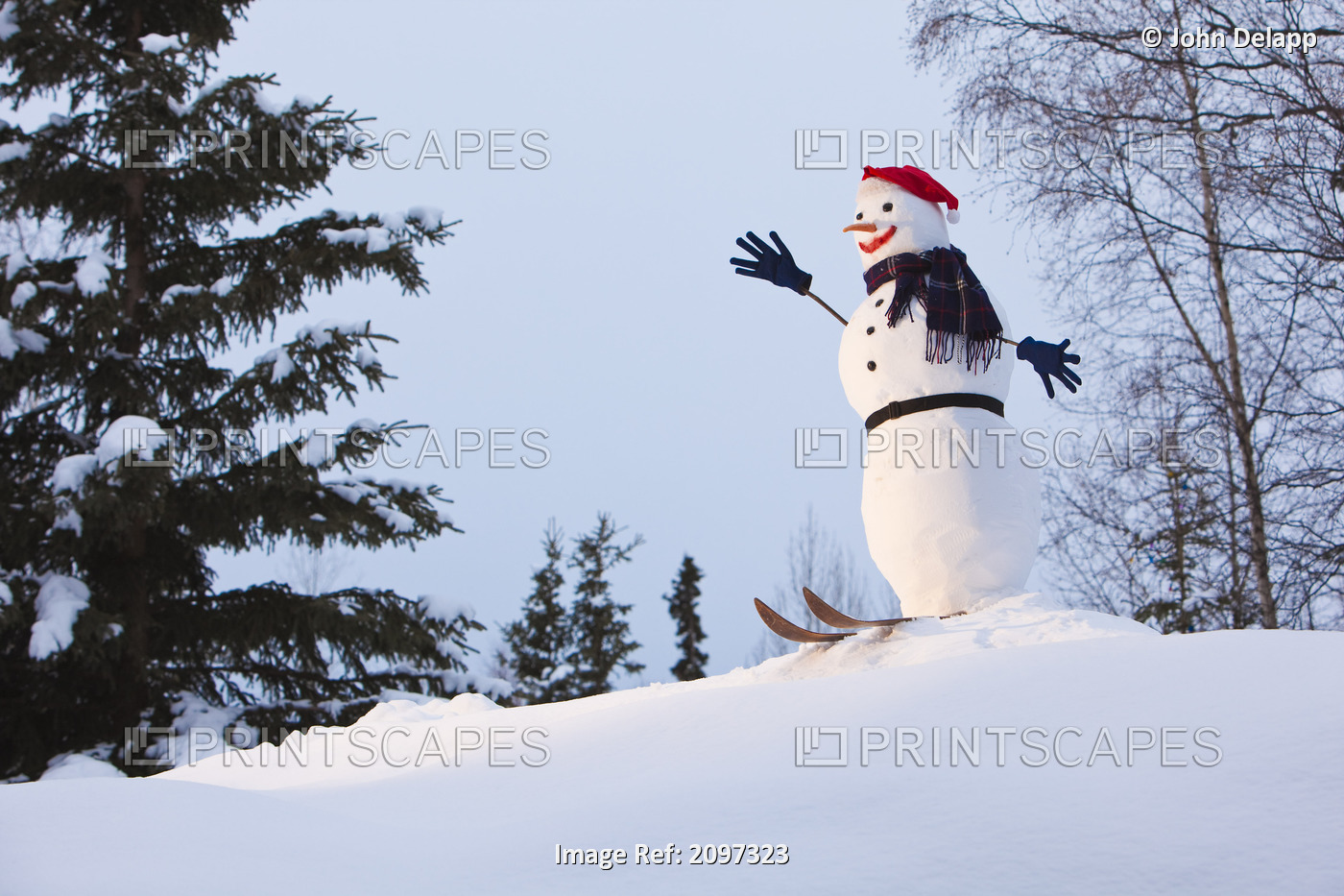 A Snowman Fitted With A Santa Hat, Gloves, And Skiis Is Perched On A Small Snow ...