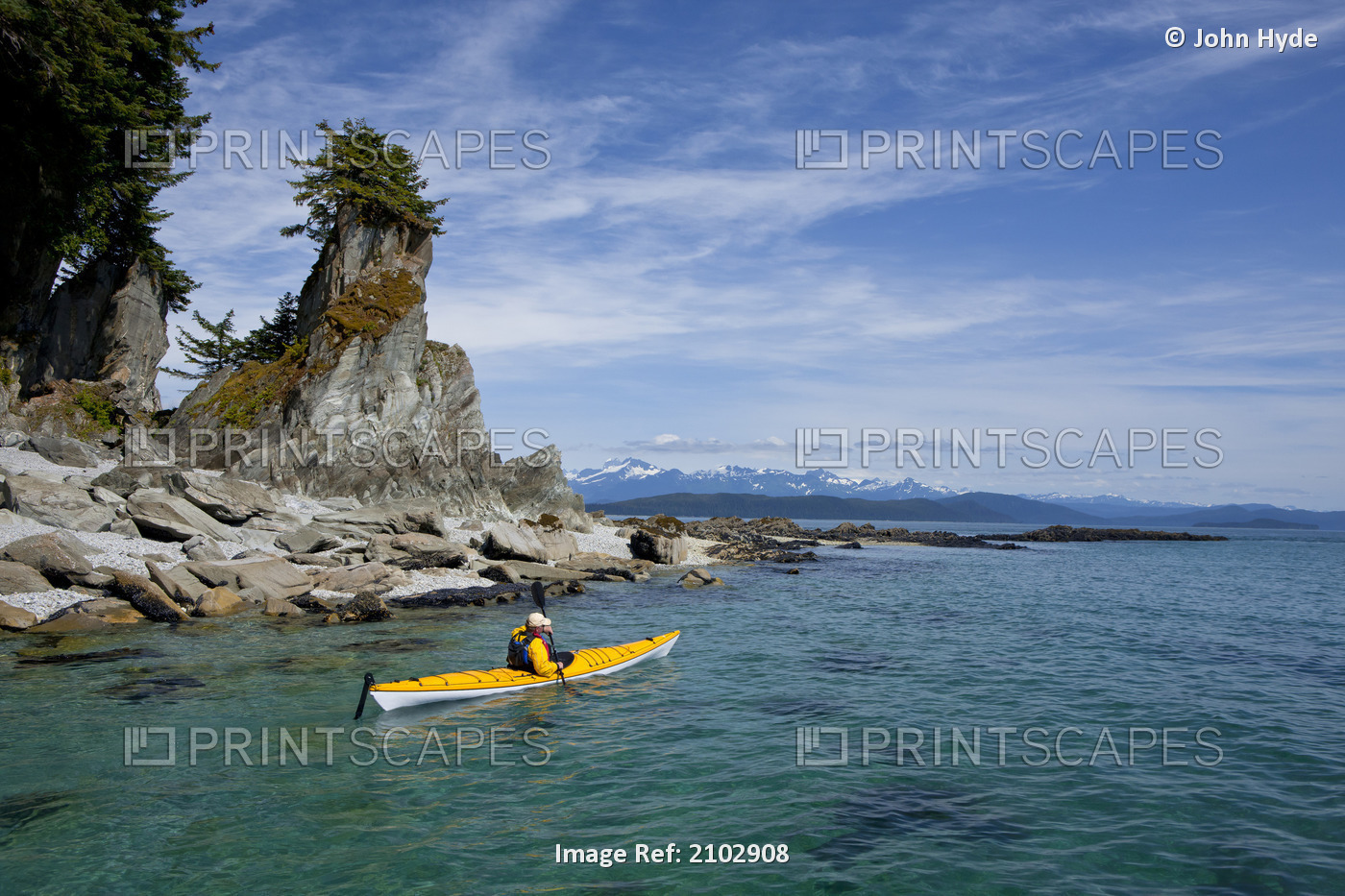 A Water Level View Of A Sea Kayaker Paddling In Calm Waters Along A Shoreline ...