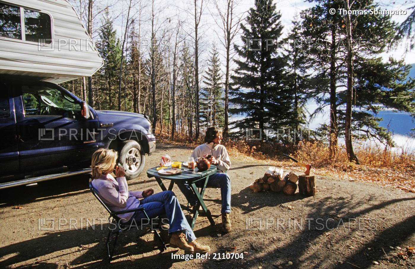 Couple Enjoy Breakfast Next To A Lake While Travelling In Their Pick-Up Camper ...