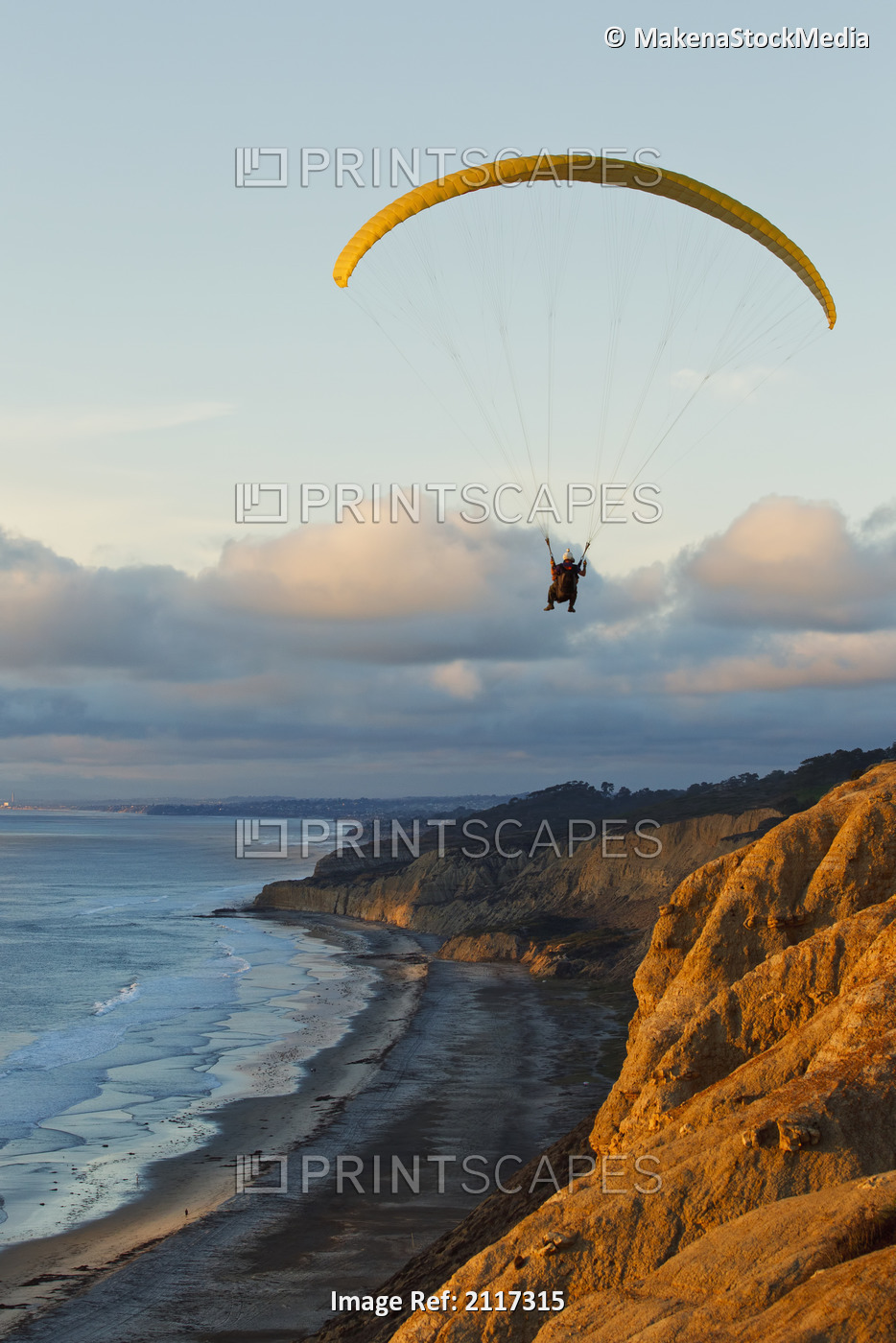 California, La Jolla, Paraglider flying over ocean cliffs at sunset. EDITORIAL ...