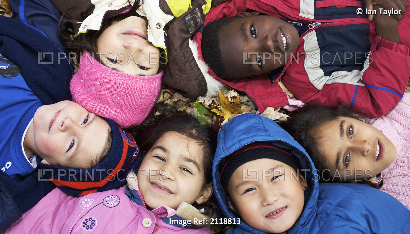 Multi-Ethnic New Canadian Children Lying In Autumn Leaves Outside Esl School; ...