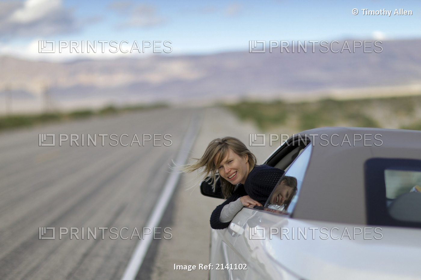 A Young Woman Leaning Out Of Her Car Window On A Deserted Road In The Desert On ...