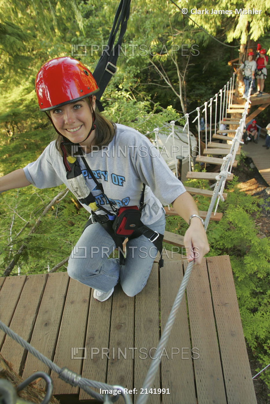 Young Woman Crossing Rope Bridge In Rainforest Canopy Near Ketchikan, Alaska