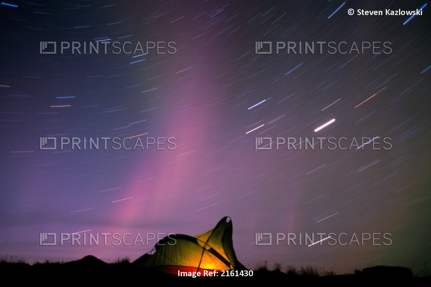 Aurora & Star Trails In Sky Over Lit Tent Near Haul Road