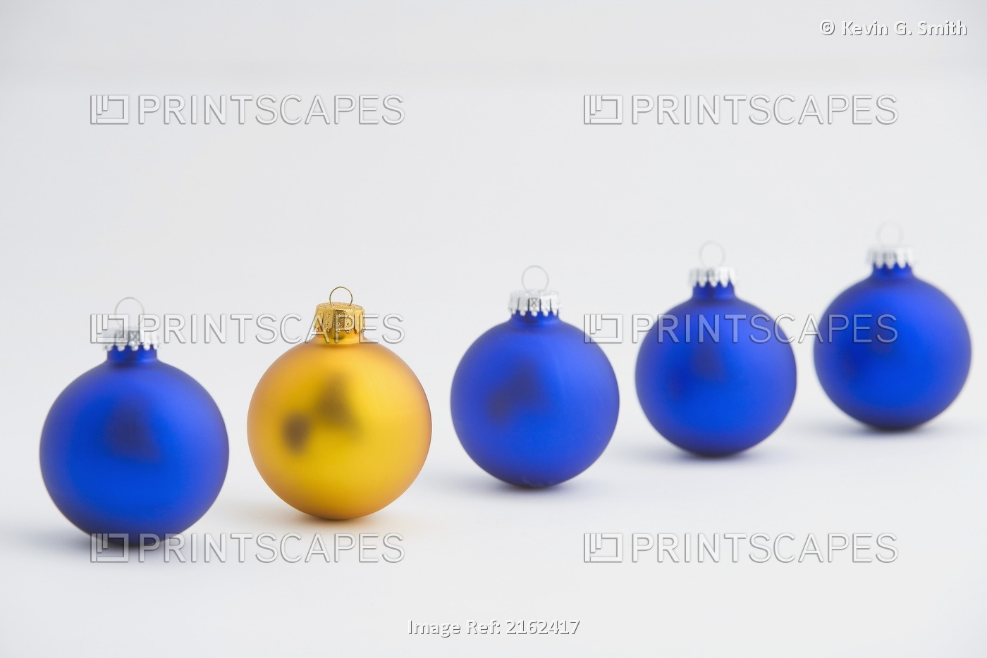 Four Blue Christmas Tree Balls Stand In Line With One Gold Ball Near Front
