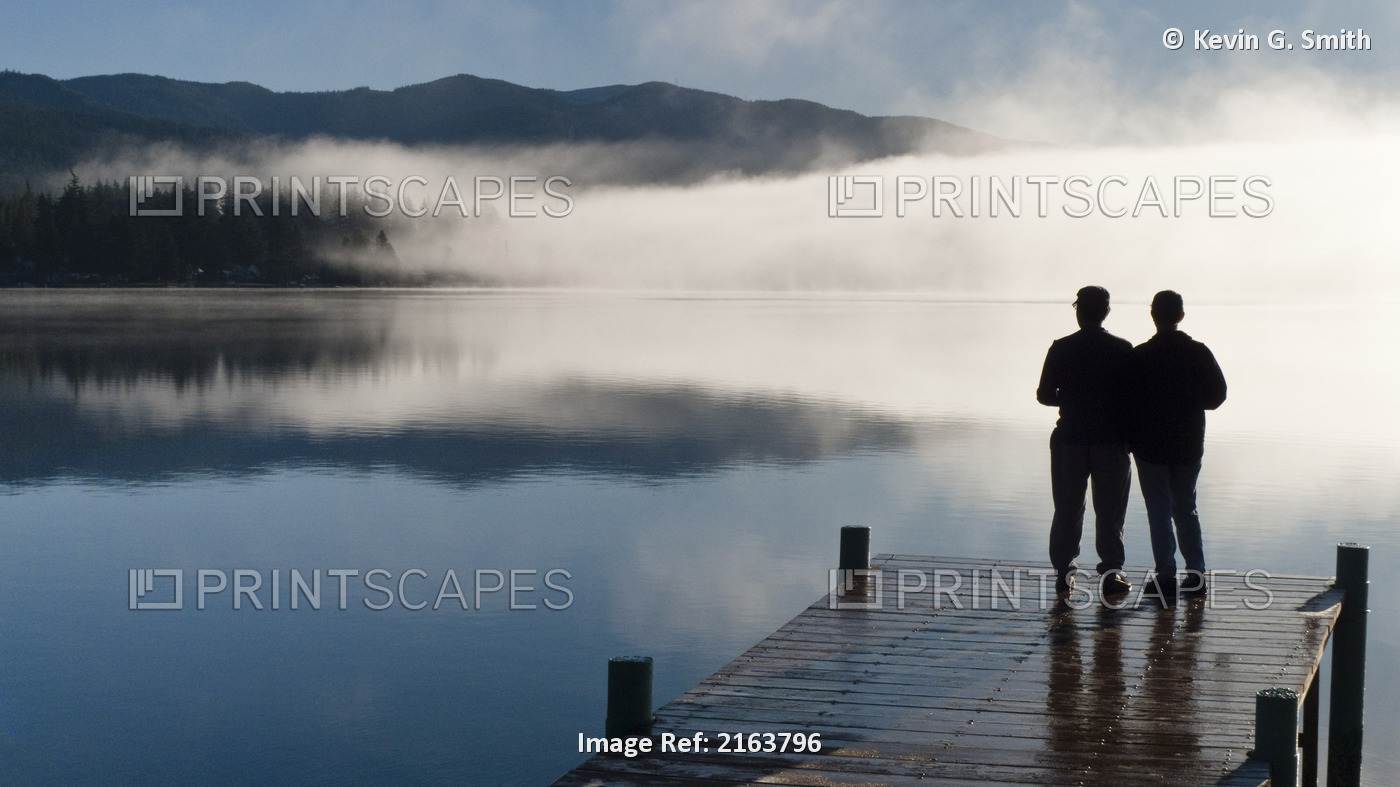 Couple Standing On A Dock And Silhouetted Against The Fog Lifting From Lake ...