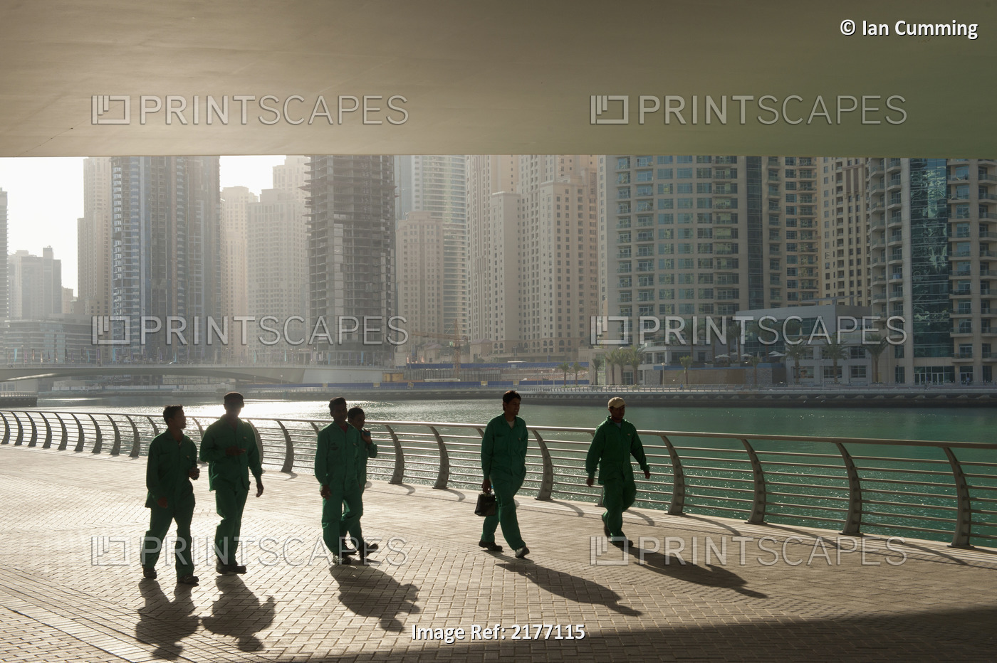 UAE, Construction workers walking under bridge in Dubai Marina; Dubai