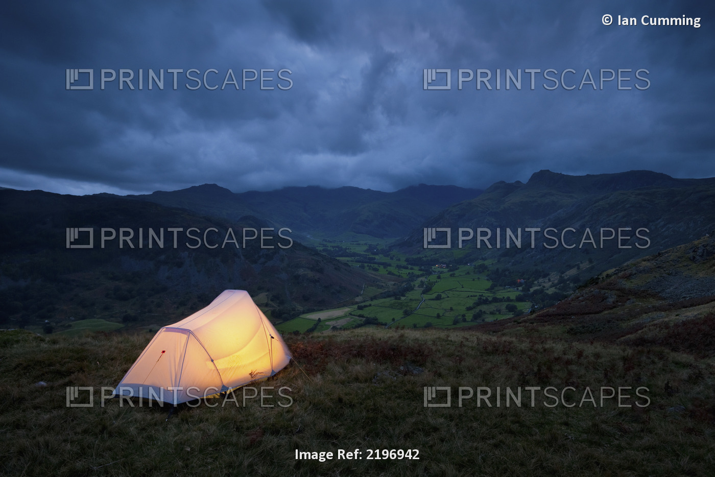 England, Cumbria, Lit tent on hill above Langdale on stormy evening; Lake ...