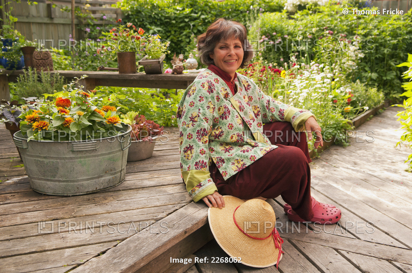 A Woman Sitting On Her Backyard Deck Surrounded By Plants And Flowers; Winnipeg ...